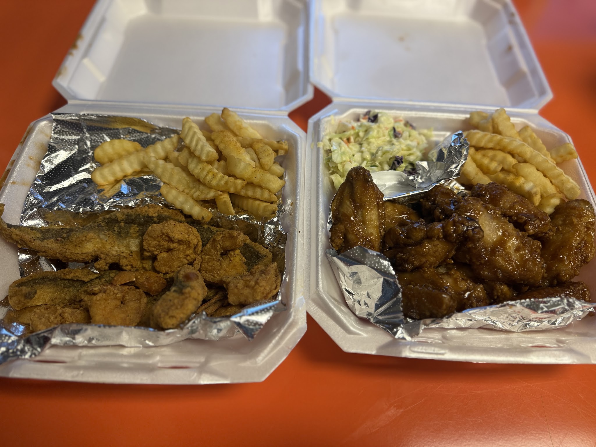 Fried fish and shrimp plate next to glazed wings with fries and slaw