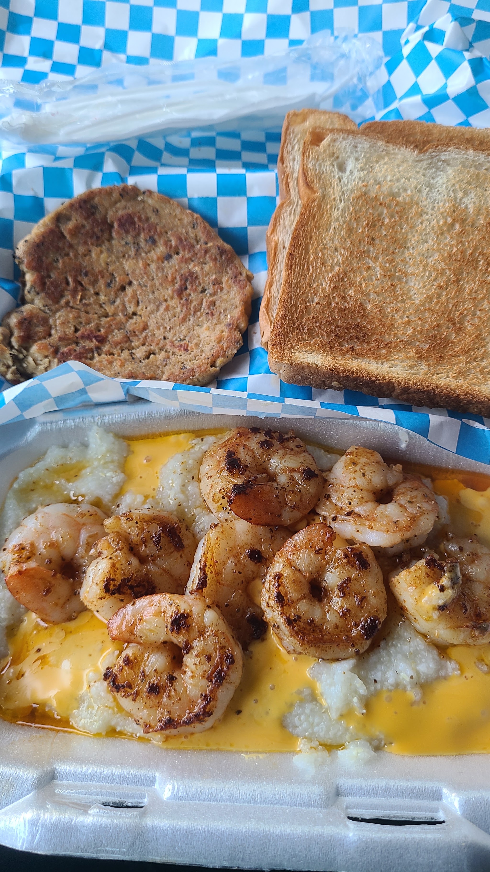 Shrimp over cheesy grits with a patty and toast